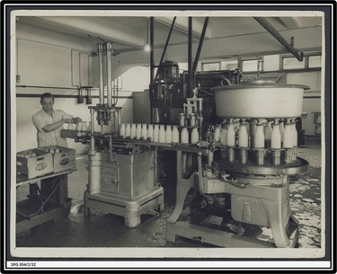 1935 Bottling milk at SA Farmers' Co-Op Union Ltd., Mile End  A Milwaukee one pint milk bottle filling machine at SA Farmers' Co-Op Union Ltd. Dairy Produce Department, Mile End. A man is packing the filled bottles into wooden crates marked with the SA Farmers' Co-Op Union logo.