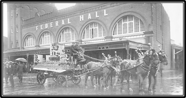 1912 Draught horses decorated with brasses and ribbons pulling a cart carrying a trade display for  Henry Jones IXL jams in Grote Street, Adelaide; the Federal Hall building  in the background is part of the Central Market complex [SLSA PRG 280/1/14/587]