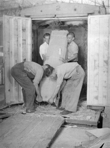 Loading petrol pump into container for transport c.1940